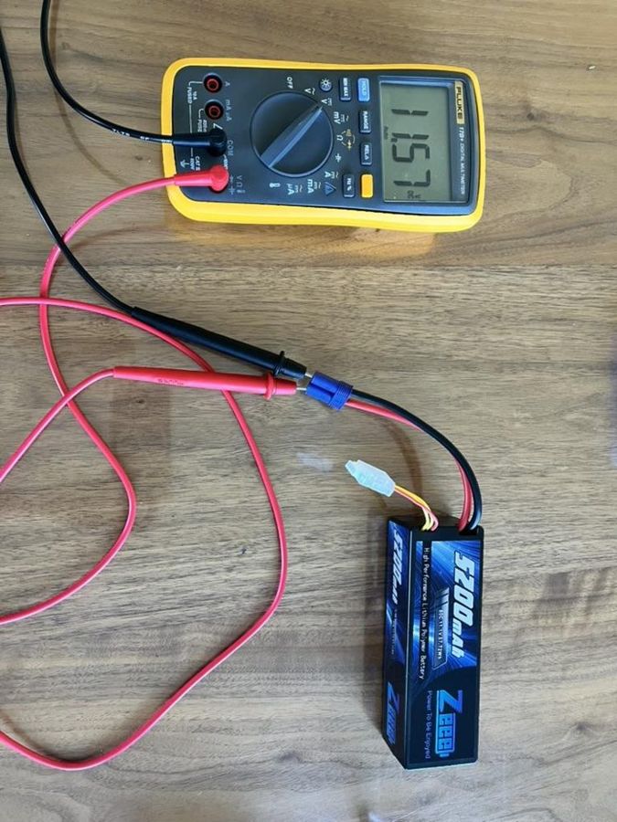 The multimeter's probes connected to a robot battery, showing a voltage reading