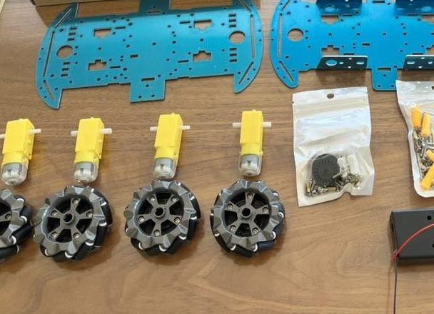 Level 1 parts laid out on a table: a metal frame, four yellow motors, wheels, and screws